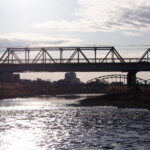 川面に映る朝日と「渡良瀬橋」の写真です。