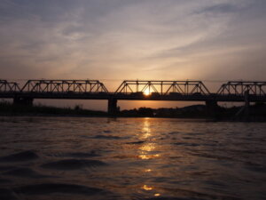 西の空にだんだん沈む夕日を背景にした渡良瀬橋の写真です。