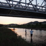 渡良瀬橋の下で釣りを楽しむ少年たちの写真です。