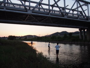渡良瀬橋の下で釣りを楽しむ少年たちの写真です。