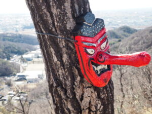 天狗山山頂の木に付けられた赤い天狗のお面の写真です。