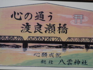 社殿の前に立つ渡良瀬橋の絵馬プレートの写真です。
