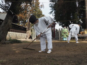 御厨神社御田植：クワでくろ塗りする写真です。